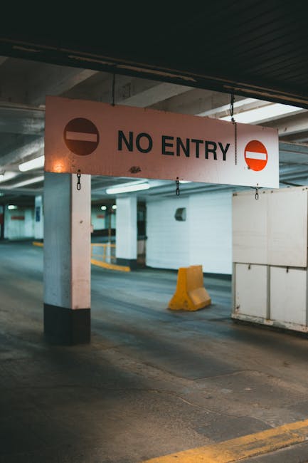 A round road sign with a blue background and a red border, displaying a red cross and two white arrows pointing left and right, indicating parking restrictions. The sign is mounted on a metal pole and